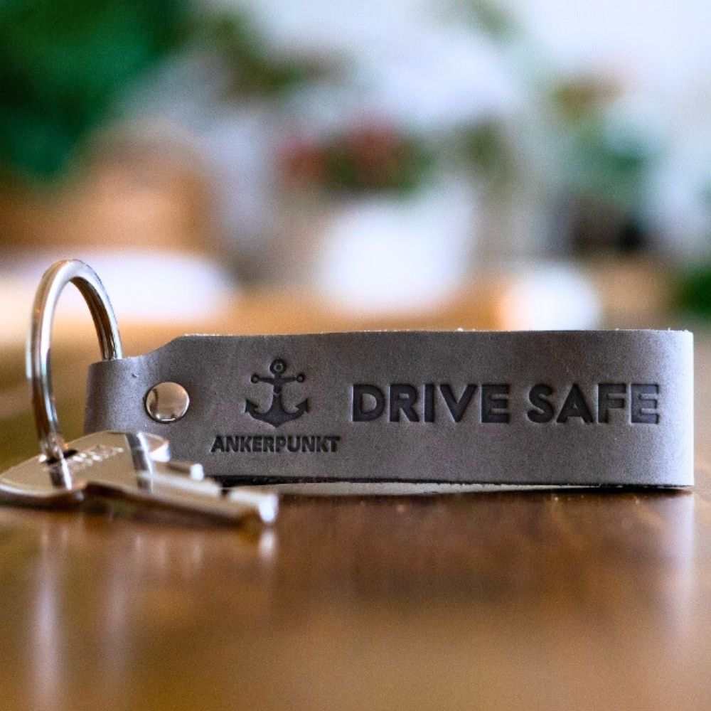 Gray leather "Drive Safe" keychain by Ankerpunkt, made in Germany, shown on a table with attached keys.
