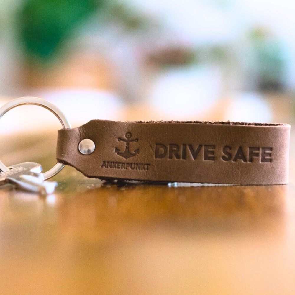 Drive Safe Schlüsselanhänger aus dunkelbraunem Leder mit graviertem Text, ideal als Geschenk für Autofahrer.