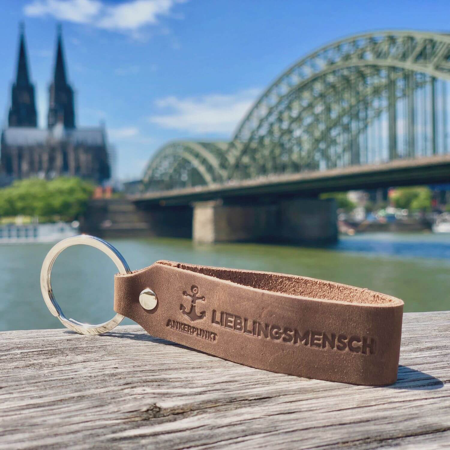Schlüsselanhänger mit Gravur Lieblingsmensch auf Holz am Rhein, im Hintergrund ist der Kölner Dom zu sehen