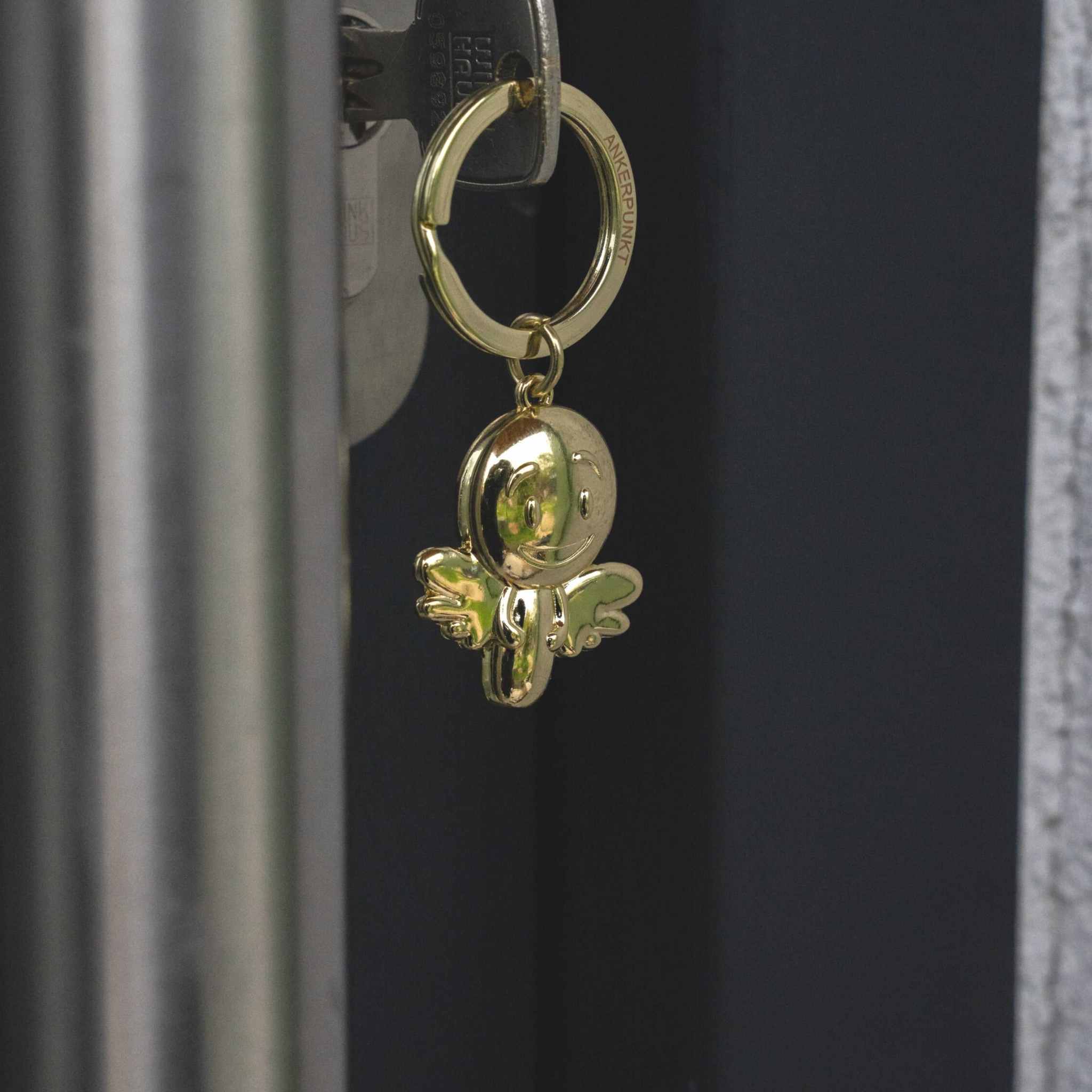Gold shiny angel smiley keyring attached to a door key.