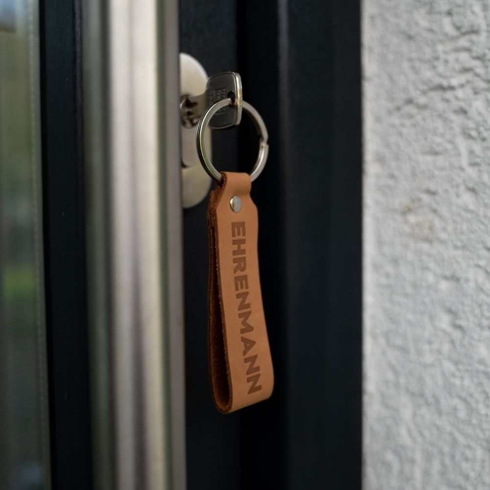 Light brown leather keychain set "Ehrenmann & Ehrenfrau" in a door lock.