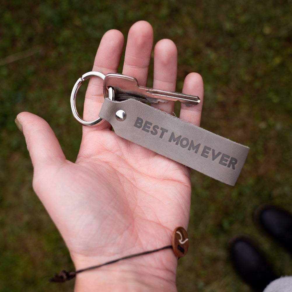Gray leather keychain with engraving "Best Mom Ever" held in hand, ideal as a special gift for mothers, made in Germany with durable full-grain leather.