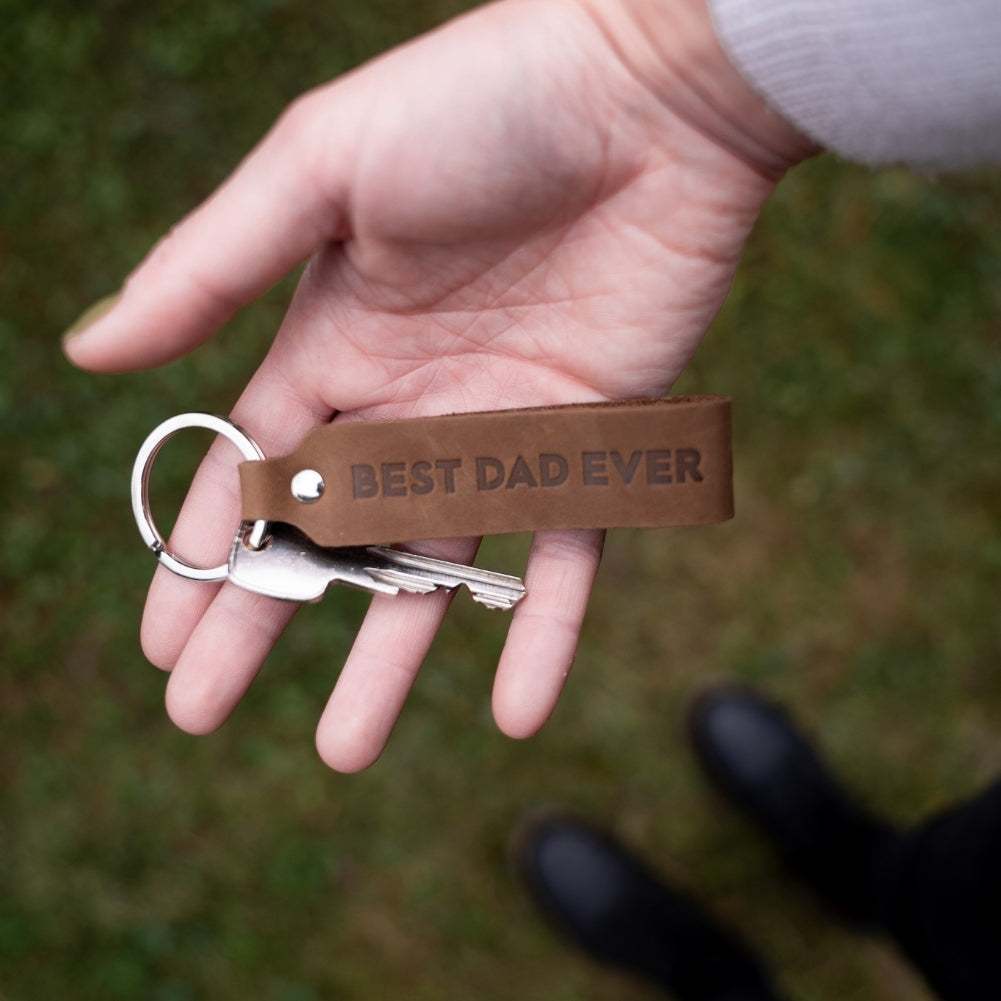 ANKERPUNKT Schlüsselanhänger Leder mit Gravur "Best Dad Ever" in Dunkelbraun held in hand.