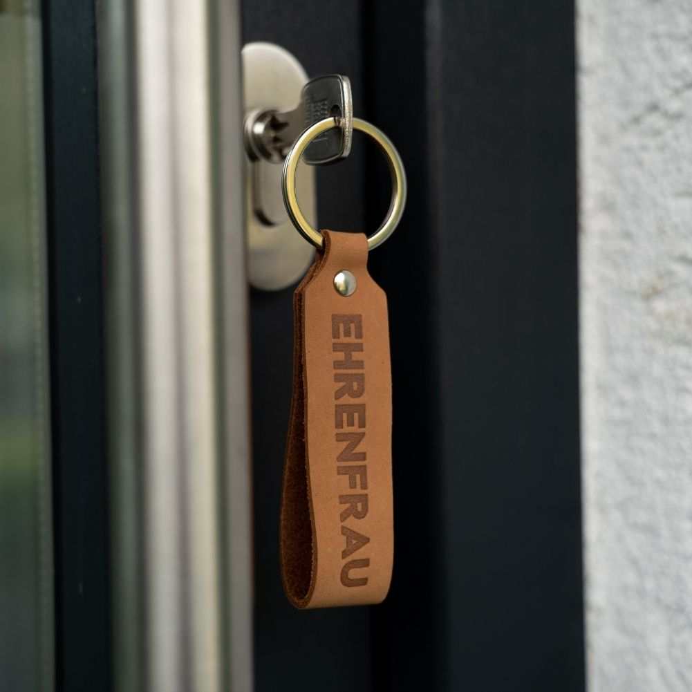 Hellbrauner Leder-Schlüsselanhänger "Ehrenfrau" ins Schlüsselloch eingesteckt.