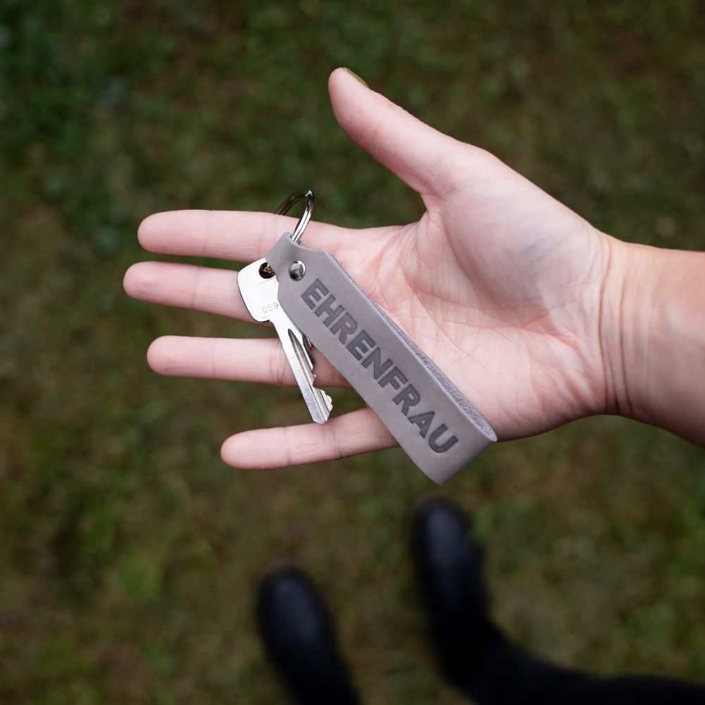 Gray leather keychain set "Ehrenmann & Ehrenfrau" in hand, perfect couples gift, made in Germany.