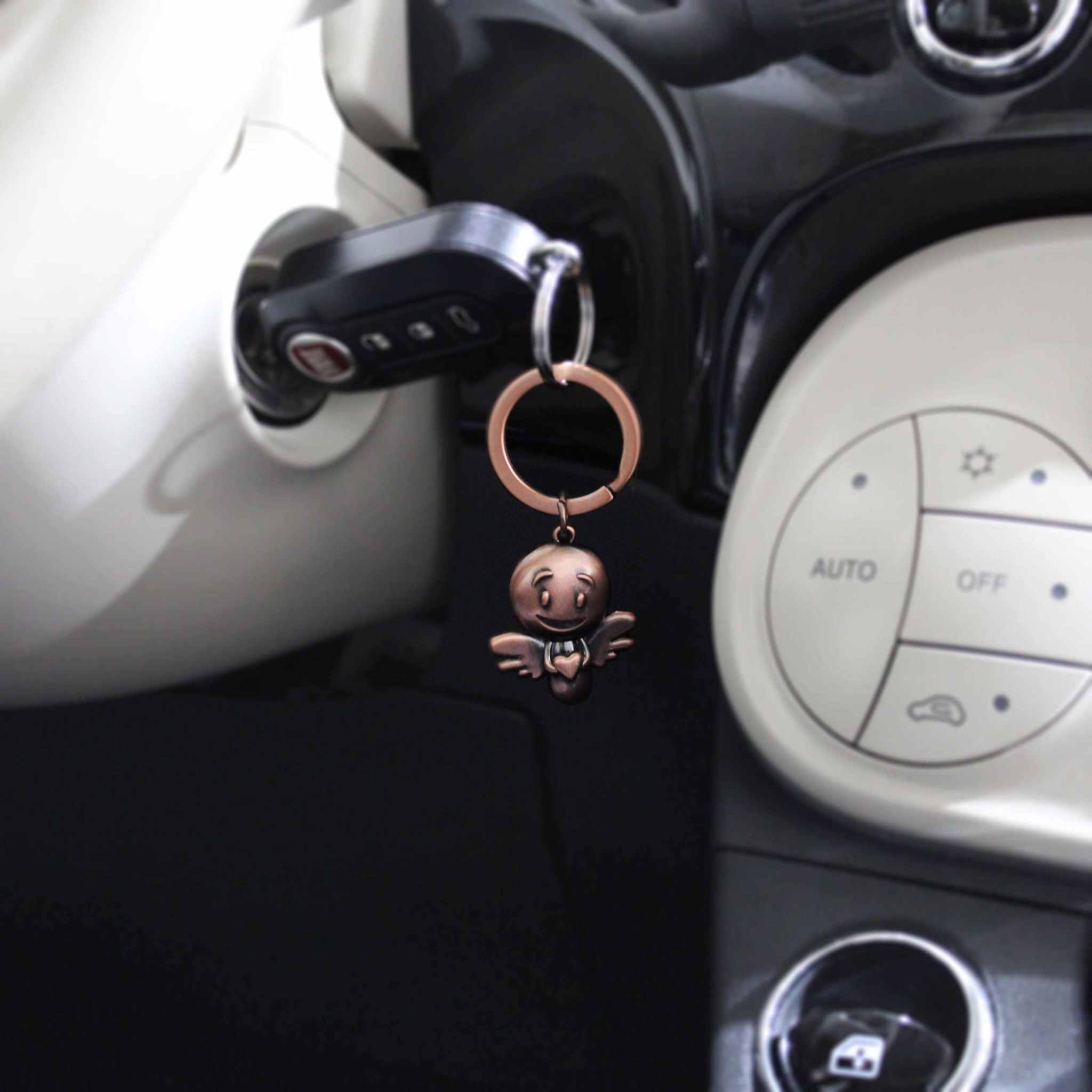 Bronze vintage guardian angel keychain in car ignition.