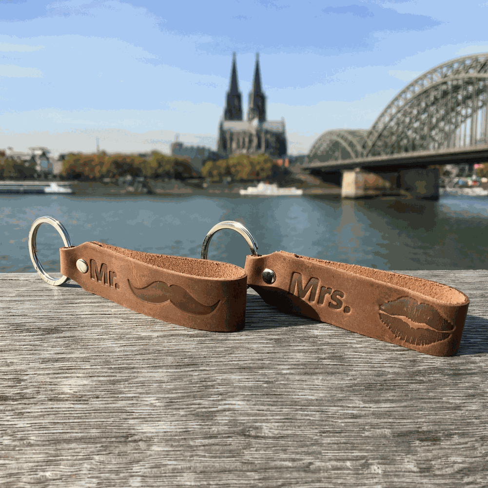 Leather keychain set with "Mr." and "Mrs." engraving, Ankerpunkt, dark brown, Cologne backdrop.