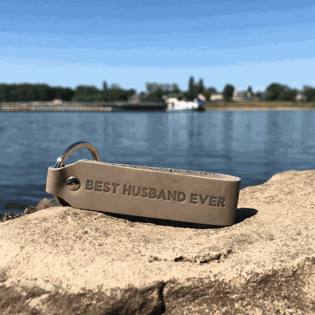Leder Schlüsselanhänger mit Gravur "Best Husband Ever" auf Felsen am Wasser.