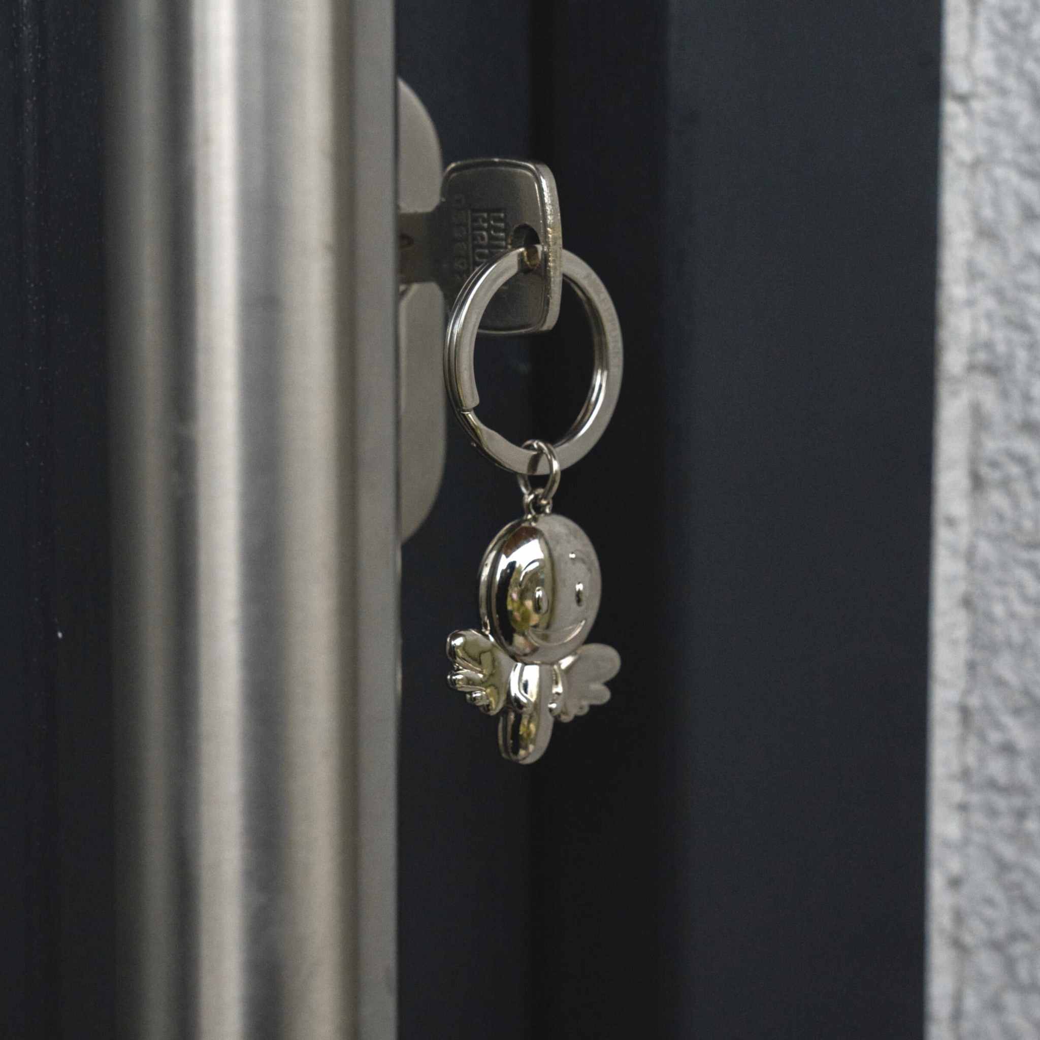 Shiny nickel guardian angel keychain on a key in a lock.