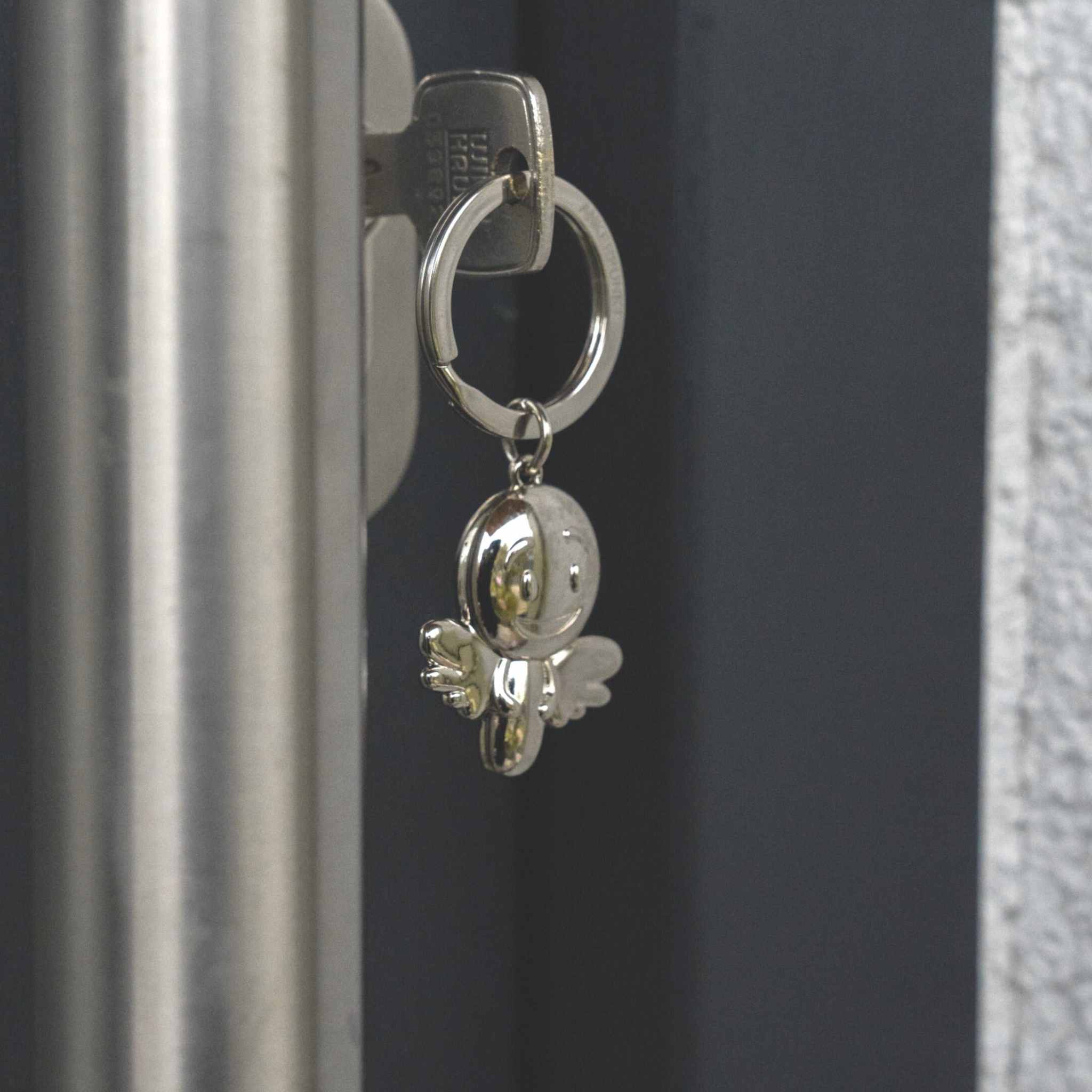 Silber glänzender Schutzengel Schlüsselanhänger mit Smiley-Design.